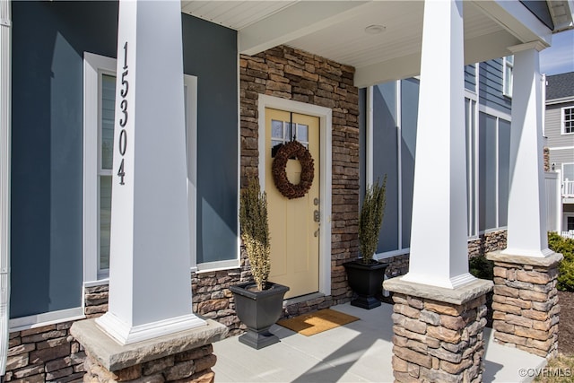 view of exterior entry with stone siding and a porch