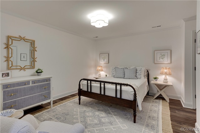 bedroom with baseboards, visible vents, crown molding, and wood finished floors