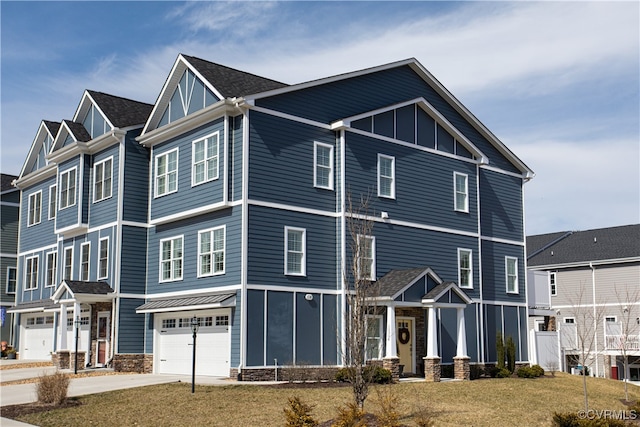 view of front of house featuring an attached garage, driveway, a residential view, board and batten siding, and a front yard