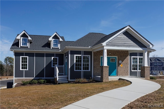 view of front of property with brick siding, roof with shingles, and a front yard