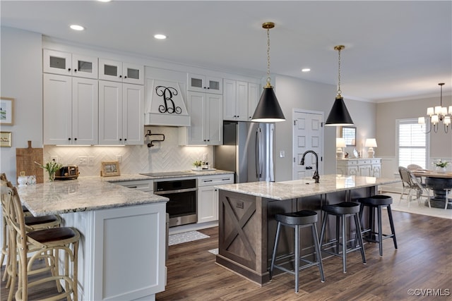 kitchen featuring appliances with stainless steel finishes, a breakfast bar, white cabinetry, and a peninsula