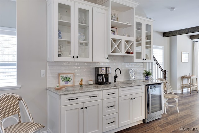 bar with beverage cooler, a sink, baseboards, dark wood-style floors, and tasteful backsplash