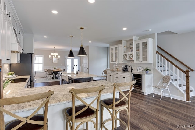 kitchen featuring beverage cooler, white cabinetry, a center island with sink, dark wood-style floors, and glass insert cabinets