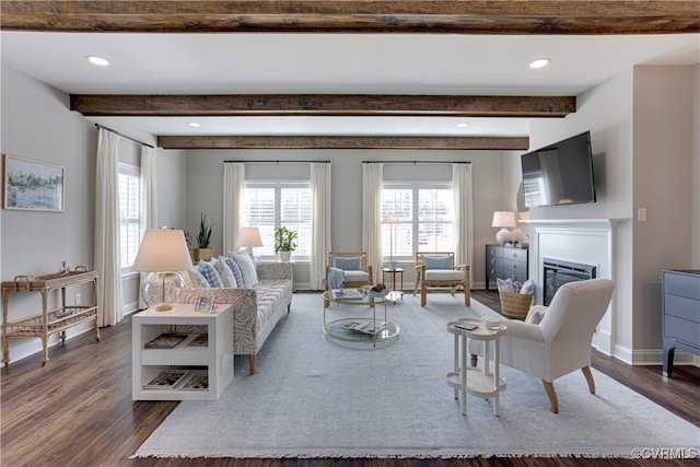 living room featuring dark wood-style floors, recessed lighting, a glass covered fireplace, beamed ceiling, and baseboards