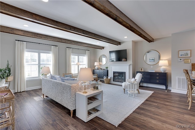 living room featuring baseboards, visible vents, a glass covered fireplace, dark wood-style floors, and beamed ceiling