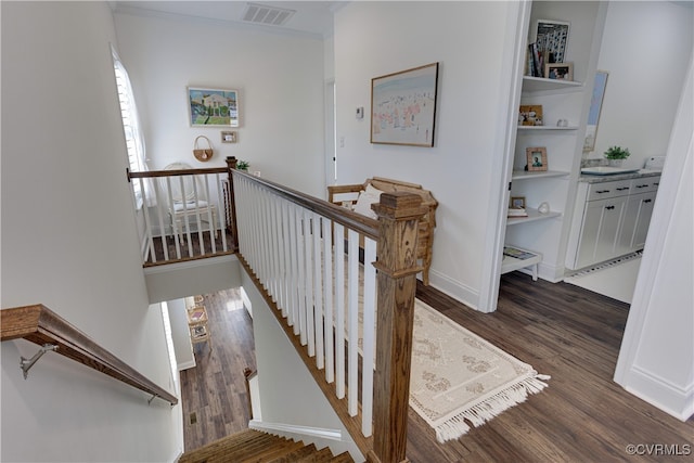 stairs with baseboards, crown molding, visible vents, and wood finished floors