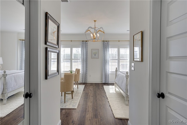 corridor featuring dark wood-style floors, visible vents, baseboards, and an inviting chandelier