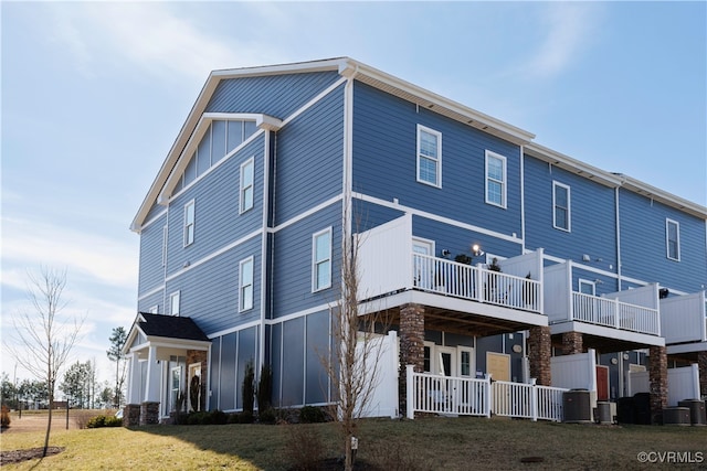 rear view of house featuring board and batten siding, a yard, and central air condition unit