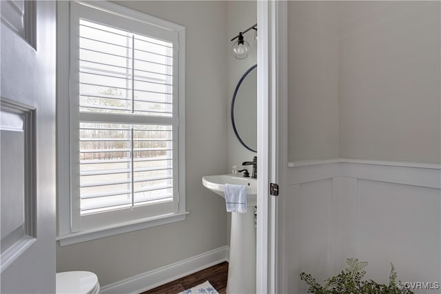 bathroom featuring toilet, a wainscoted wall, baseboards, and wood finished floors