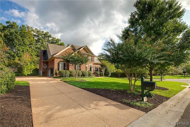 view of front facade with a front yard, brick siding, and driveway