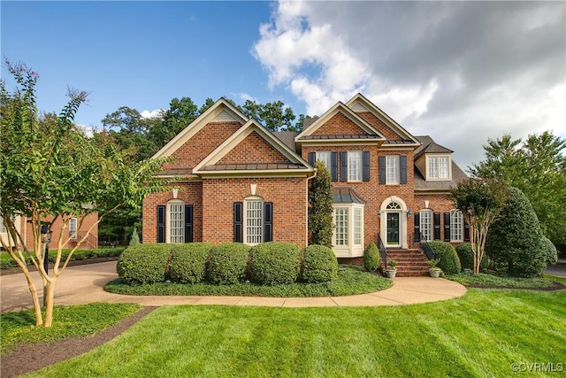 view of front of property featuring a standing seam roof, metal roof, a front lawn, and brick siding