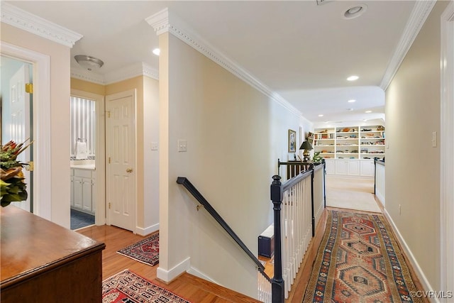 hall featuring light wood-style floors, recessed lighting, crown molding, and an upstairs landing