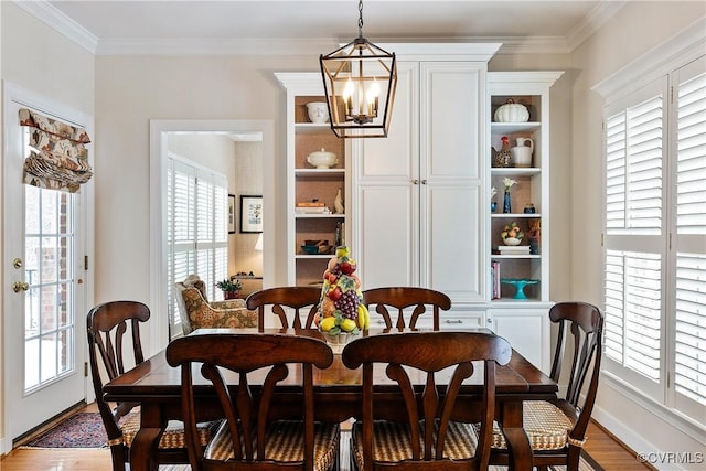 dining area with ornamental molding, wood finished floors, and a notable chandelier