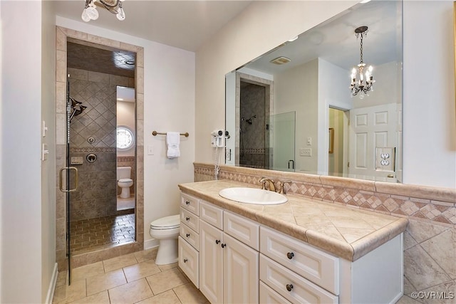 full bathroom with toilet, tile patterned floors, vanity, a shower stall, and a notable chandelier