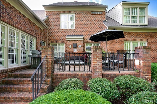 exterior space featuring roof with shingles and brick siding