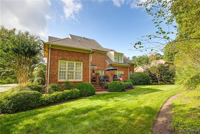 back of house with brick siding and a lawn