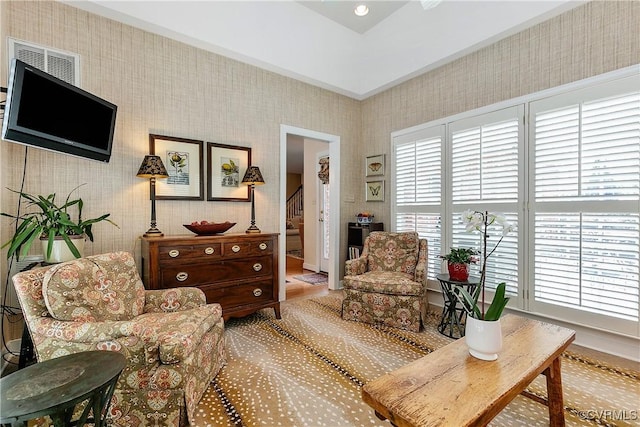 living area with stairs, visible vents, and wallpapered walls