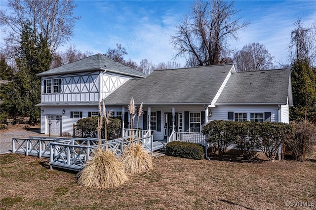 view of front of home with covered porch, a front lawn, and roof with shingles