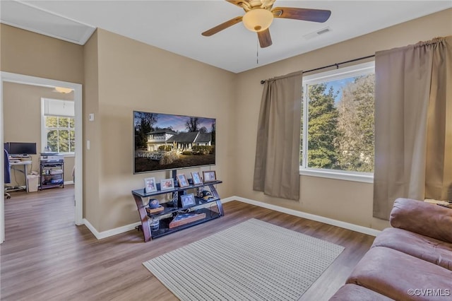 living room with plenty of natural light, wood finished floors, visible vents, and baseboards