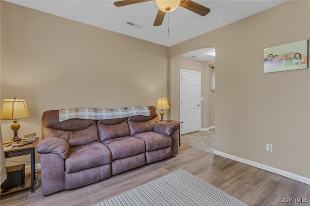 living area with baseboards, visible vents, arched walkways, ceiling fan, and wood finished floors