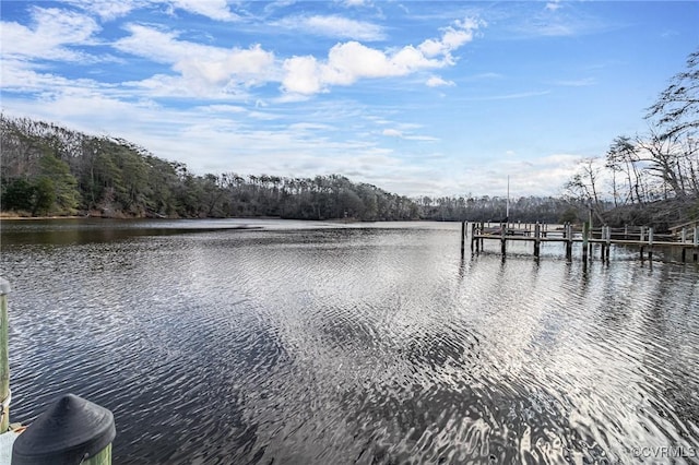 view of water feature featuring a dock and a wooded view