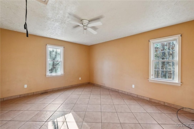 spare room with light tile patterned floors, plenty of natural light, a textured ceiling, and a ceiling fan