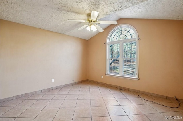 unfurnished room with light tile patterned floors, a textured ceiling, a ceiling fan, baseboards, and vaulted ceiling