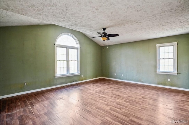 empty room with plenty of natural light, a textured ceiling, and wood finished floors