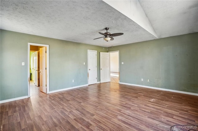 spare room with ceiling fan, a textured ceiling, baseboards, and wood finished floors