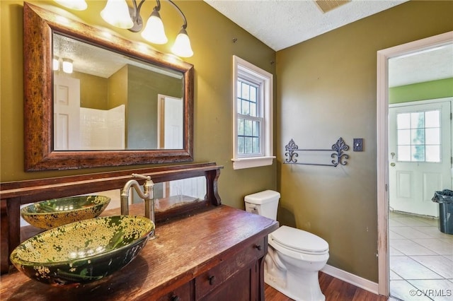 bathroom with visible vents, baseboards, toilet, a textured ceiling, and vanity