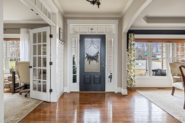 entryway with arched walkways, ornamental molding, hardwood / wood-style flooring, and a wealth of natural light