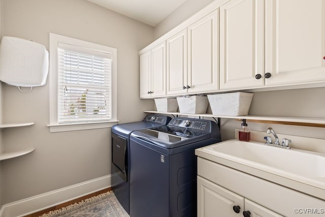 clothes washing area featuring cabinet space, baseboards, separate washer and dryer, and a sink