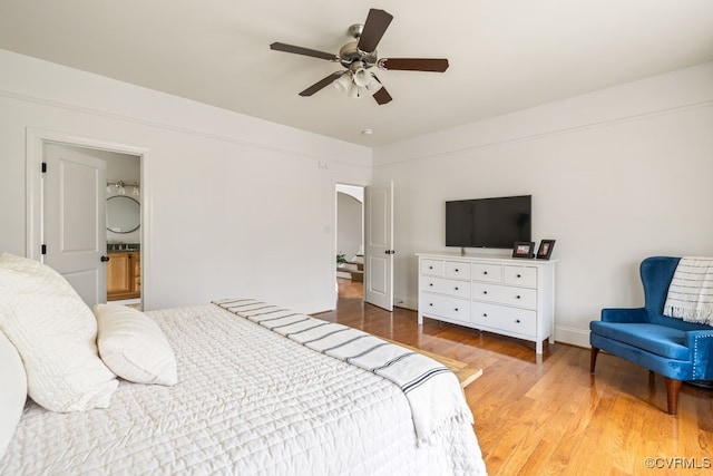 bedroom featuring ensuite bath, wood finished floors, a ceiling fan, and baseboards