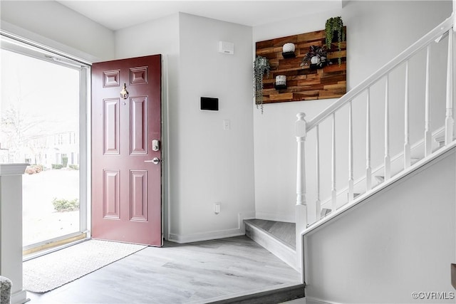 foyer entrance featuring wood finished floors, baseboards, and stairs