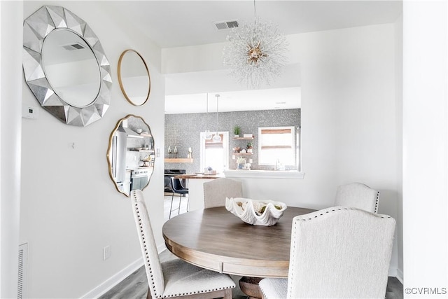 dining area featuring wood finished floors, visible vents, baseboards, and an inviting chandelier