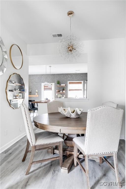 dining space featuring an inviting chandelier, baseboards, visible vents, and wood finished floors