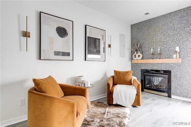 living area with a fireplace, wood finished floors, and baseboards