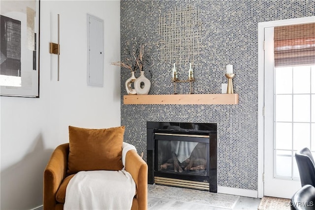 sitting room featuring a tiled fireplace, a wealth of natural light, and electric panel