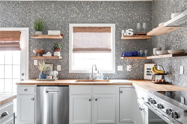 kitchen with butcher block counters, a sink, appliances with stainless steel finishes, backsplash, and open shelves