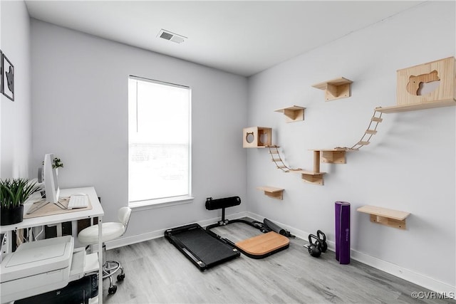 exercise room with wood finished floors, visible vents, and baseboards