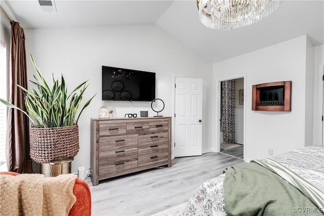 bedroom featuring vaulted ceiling, light wood finished floors, a chandelier, and visible vents