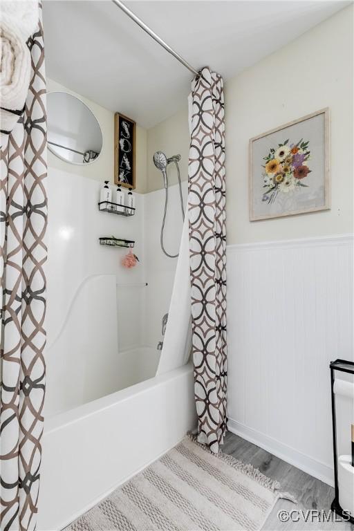 full bathroom featuring wainscoting, wood finished floors, and shower / bathtub combination with curtain