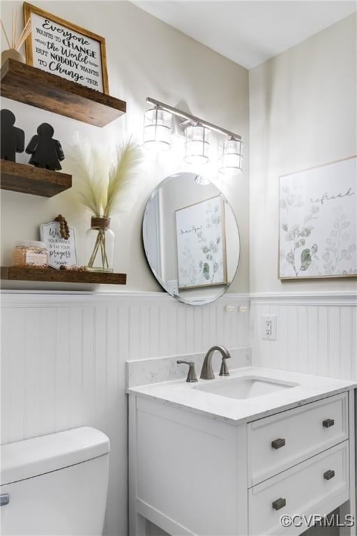 bathroom with toilet, a wainscoted wall, and vanity