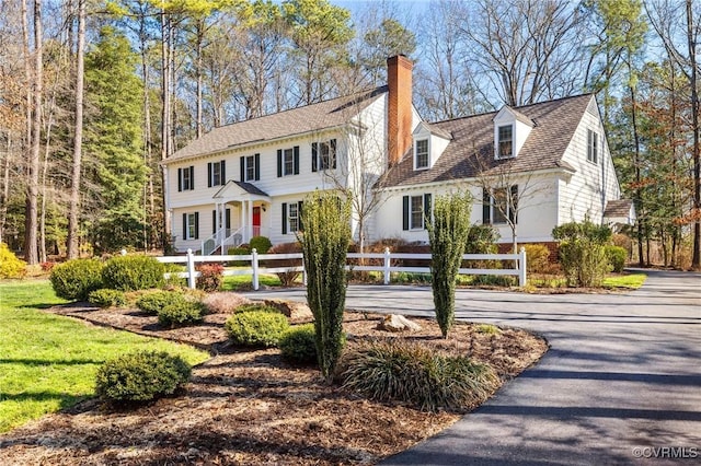 view of front of house with driveway, a fenced front yard, and a chimney