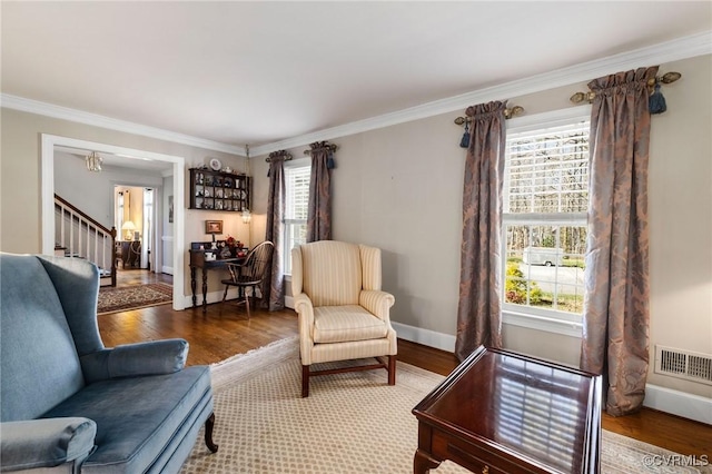 living area featuring visible vents, baseboards, stairway, wood finished floors, and crown molding