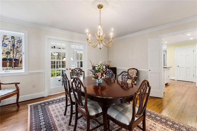 dining area with baseboards, light wood finished floors, an inviting chandelier, and crown molding