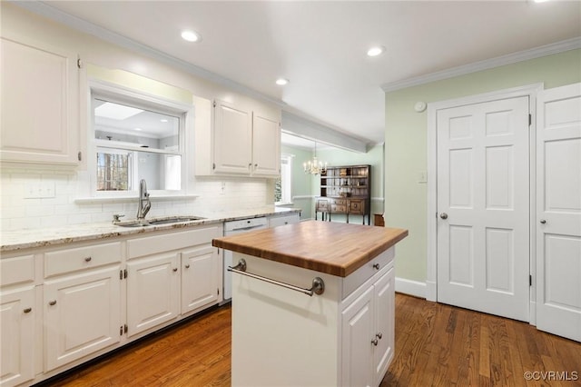 kitchen featuring butcher block counters, crown molding, dark wood-style flooring, and a sink