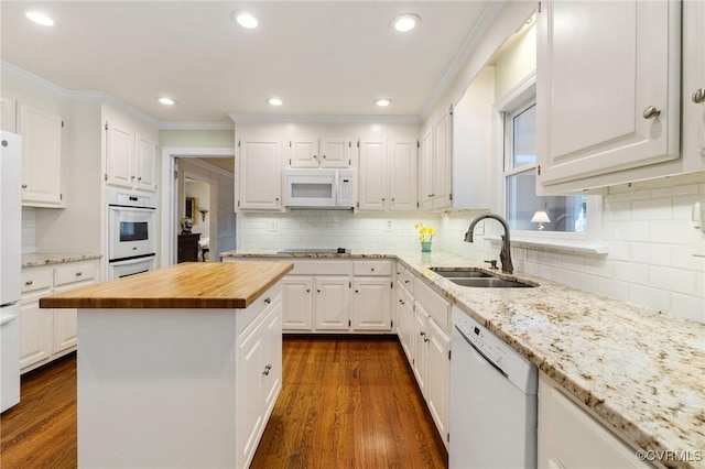 kitchen featuring white appliances, dark wood-type flooring, butcher block countertops, a sink, and white cabinetry