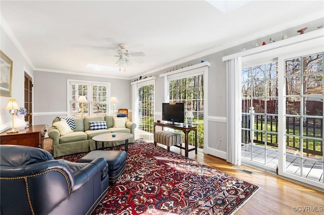 living area featuring a ceiling fan, ornamental molding, and wood finished floors