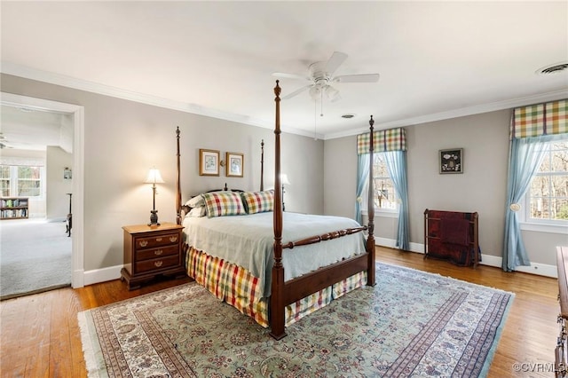 bedroom featuring ornamental molding, wood finished floors, visible vents, and baseboards